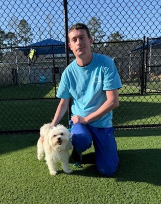 a man kneeling on grass with a dog