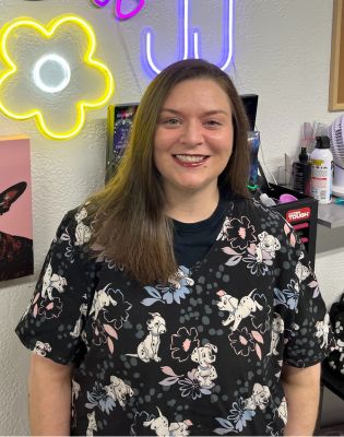 a woman smiling in front of a neon sign
