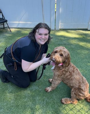 a woman kneeling on grass with a dog